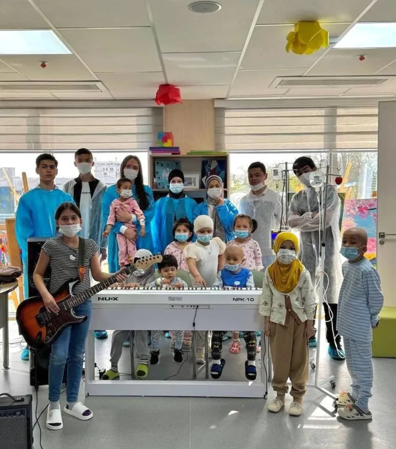 Tasanno jamoasi onkologiya markazida bolalar bilan, gitara va pianino yonida